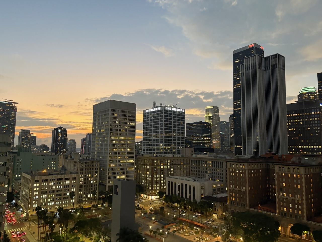 The Downtown LA skyline at sunset seen from a rooftop bar - skyscrapers lit up against a golden sky