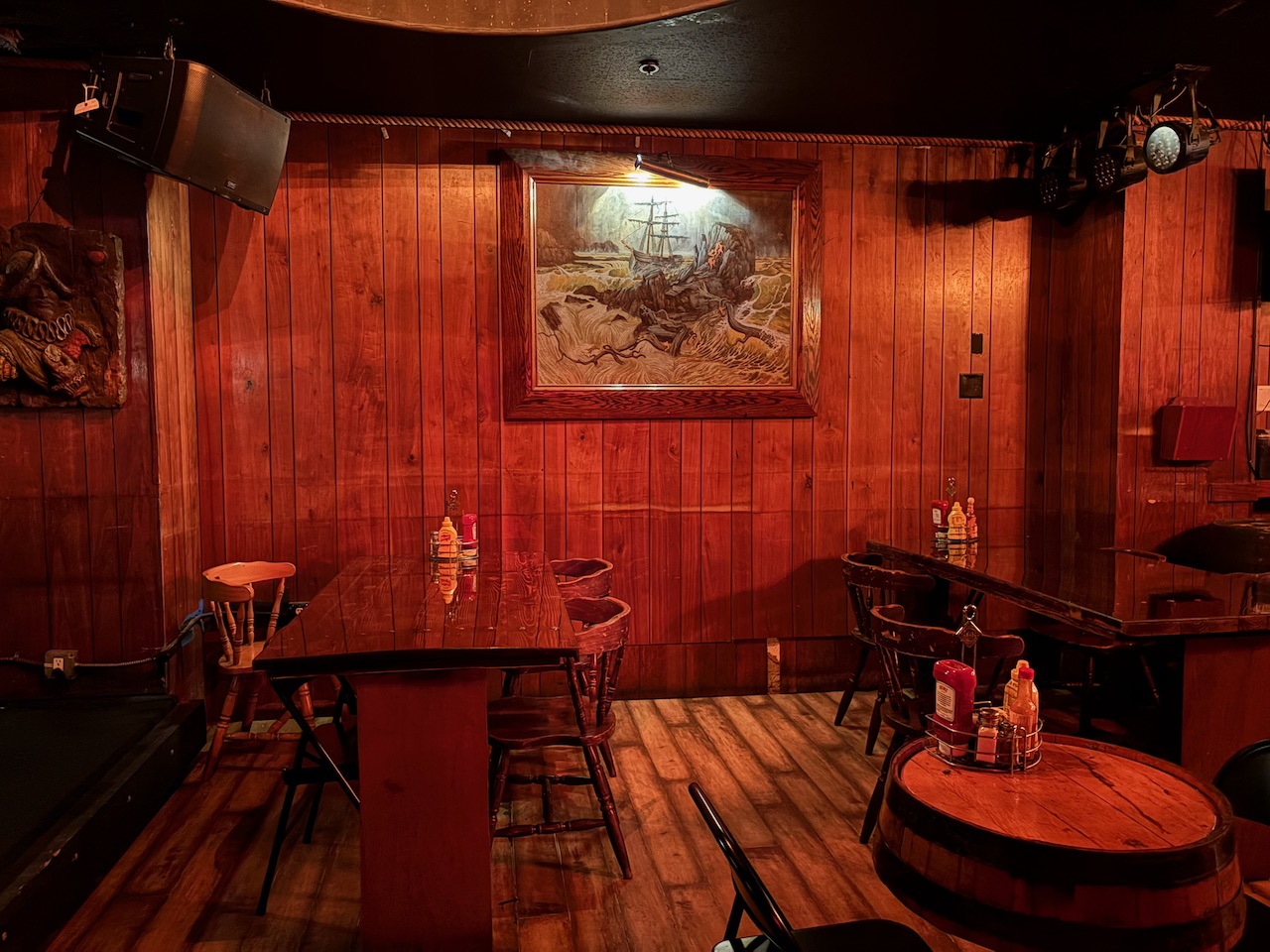 The wood-paneled interior of the Redwood Bar with an oil painting of a ship sailing through stormy seas on the wall